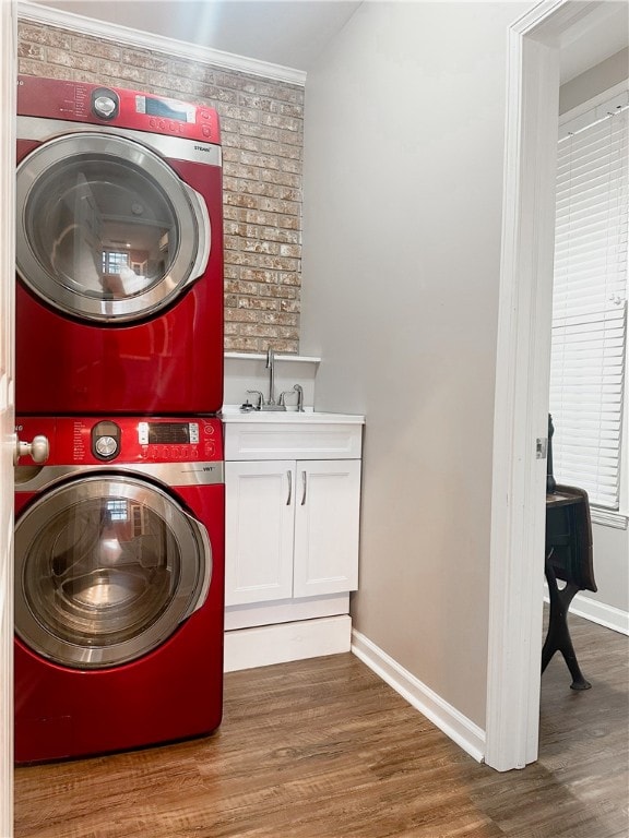 washroom featuring cabinets, stacked washer / dryer, dark wood-type flooring, sink, and ornamental molding