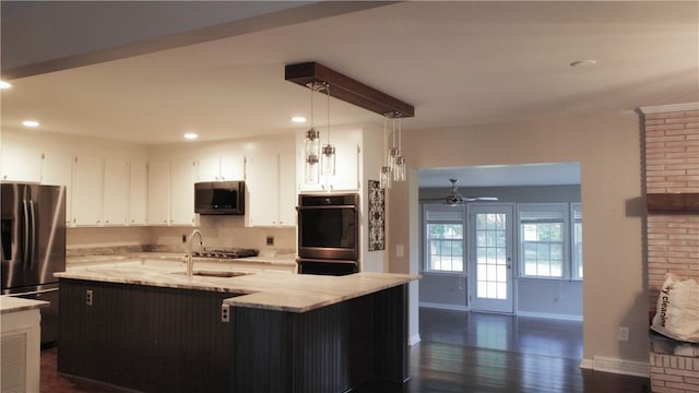 kitchen featuring sink, hanging light fixtures, a center island with sink, appliances with stainless steel finishes, and dark hardwood / wood-style flooring