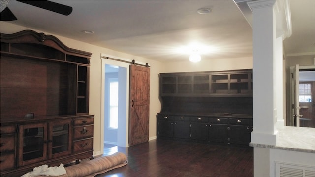 living room featuring ceiling fan, a barn door, plenty of natural light, and dark hardwood / wood-style flooring