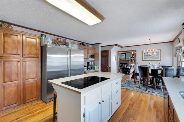 kitchen featuring stainless steel refrigerator, light wood-type flooring, a textured ceiling, and a kitchen island