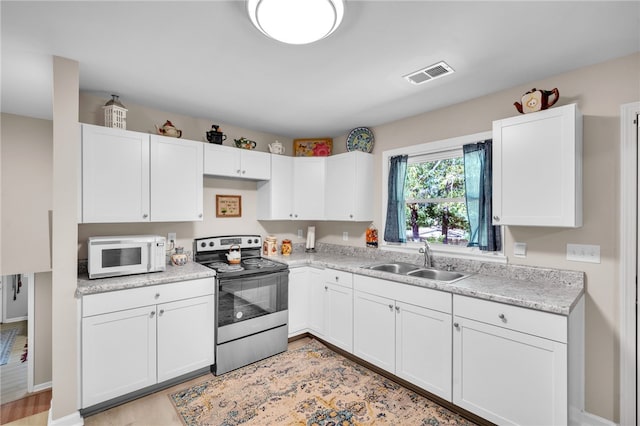 kitchen with light hardwood / wood-style floors, stainless steel electric range oven, sink, and white cabinetry