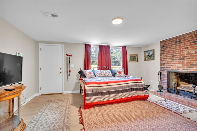 bedroom featuring a brick fireplace and light wood-type flooring