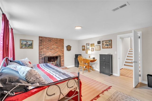 bedroom with light wood-type flooring and a fireplace