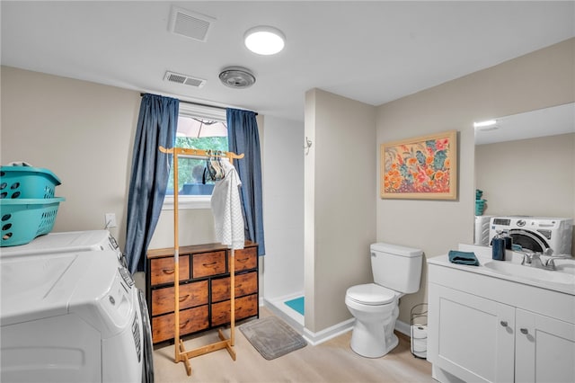 bathroom featuring washing machine and clothes dryer, vanity, hardwood / wood-style floors, and toilet