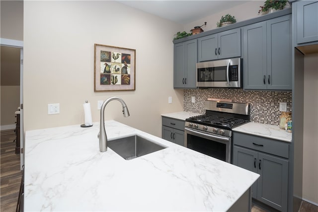 kitchen featuring light stone counters, stainless steel appliances, dark hardwood / wood-style floors, and sink