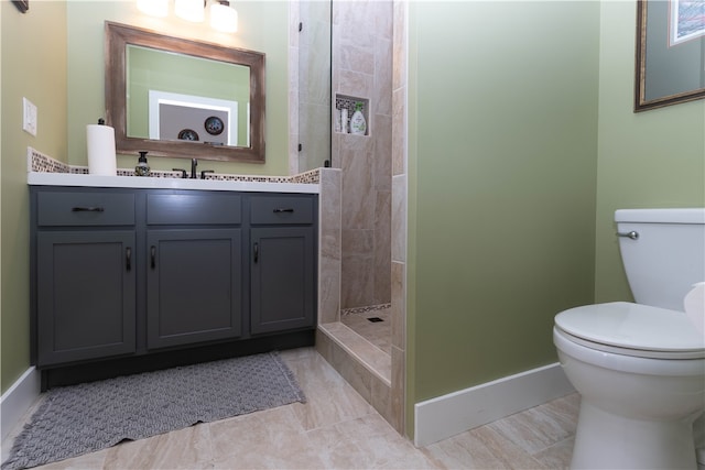 bathroom with tile patterned flooring, tiled shower, vanity, and toilet