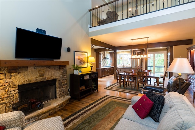 living room featuring a towering ceiling, hardwood / wood-style floors, and a stone fireplace