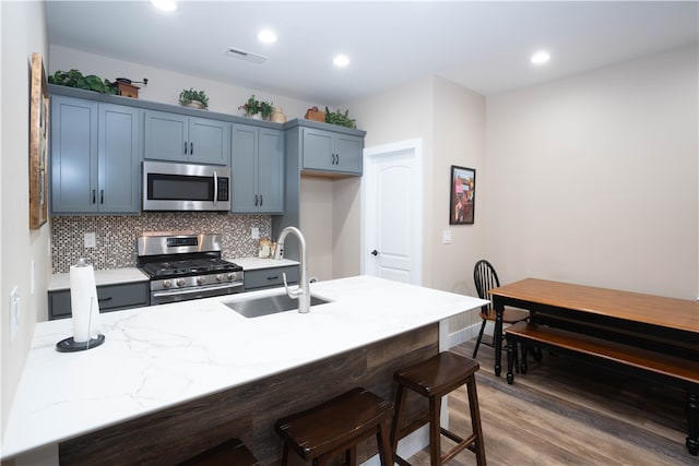 kitchen featuring decorative backsplash, dark hardwood / wood-style floors, stainless steel appliances, sink, and blue cabinets