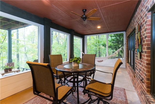 sunroom / solarium featuring plenty of natural light, wood ceiling, and ceiling fan