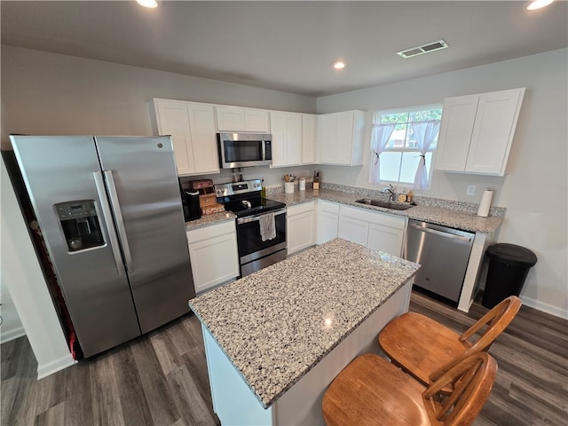 kitchen featuring appliances with stainless steel finishes, dark wood-type flooring, white cabinets, a kitchen island, and sink