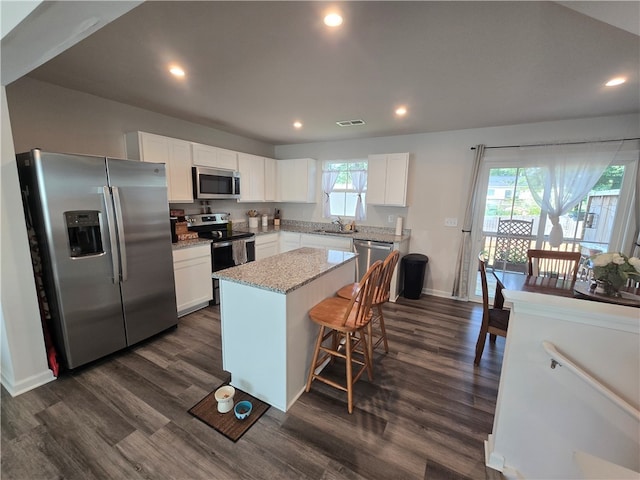 kitchen with stainless steel appliances, white cabinets, dark wood-type flooring, and a kitchen island