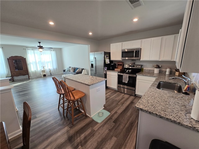 kitchen with appliances with stainless steel finishes, white cabinets, a center island, dark hardwood / wood-style floors, and sink