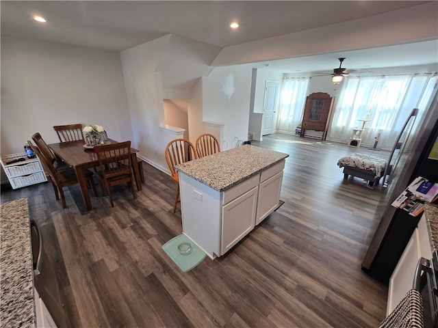 kitchen featuring light stone countertops, white cabinets, ceiling fan, and dark hardwood / wood-style flooring