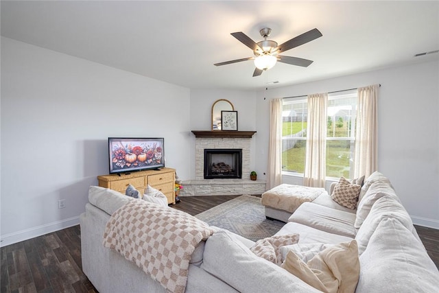 living room featuring a stone fireplace, dark hardwood / wood-style floors, and ceiling fan