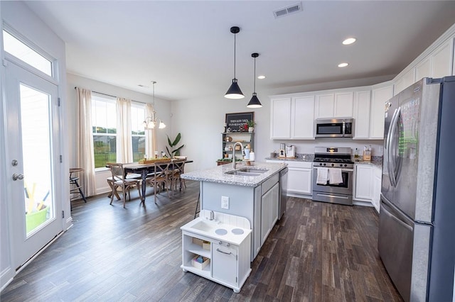 kitchen with pendant lighting, a kitchen island with sink, stainless steel appliances, and white cabinets