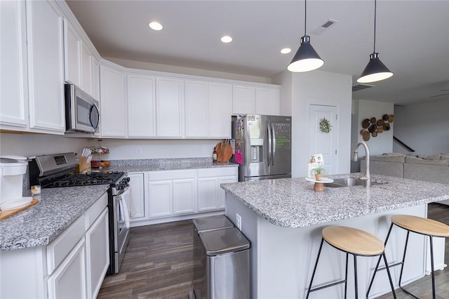 kitchen with white cabinetry, light stone counters, decorative light fixtures, and appliances with stainless steel finishes