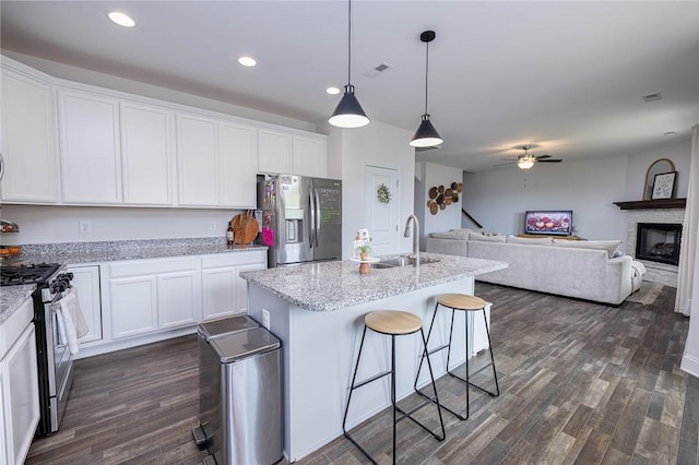 kitchen featuring stainless steel appliances, white cabinetry, pendant lighting, and a kitchen breakfast bar