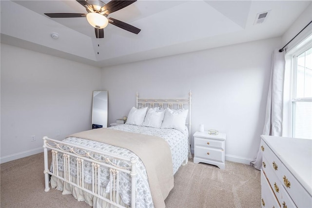 carpeted bedroom featuring a raised ceiling and ceiling fan