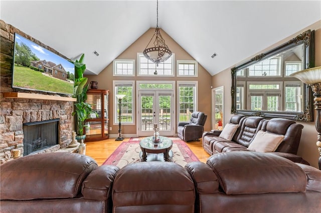 516 Serria Way, Seneca, SC 29678 - living area featuring high vaulted ceiling, light wood-type flooring, a stone fireplace, plenty of natural light, and french doors