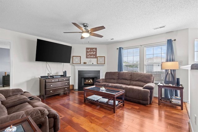 living room featuring a textured ceiling, dark hardwood / wood-style floors, and ceiling fan