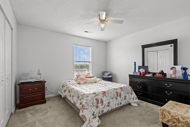 carpeted bedroom with ceiling fan and a textured ceiling