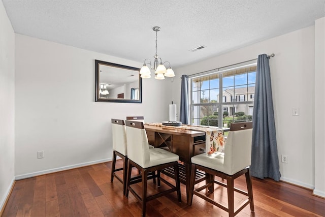 dining room with a notable chandelier, a textured ceiling, and dark hardwood / wood-style floors