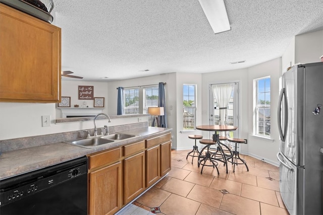 kitchen featuring dishwasher, a textured ceiling, sink, light tile patterned floors, and stainless steel fridge