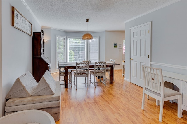 dining area featuring a textured ceiling, ornamental molding, and light hardwood / wood-style flooring