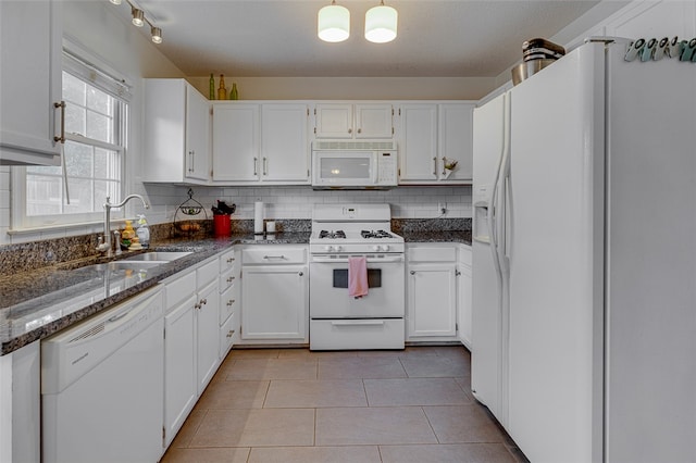 kitchen featuring light tile patterned floors, sink, white appliances, white cabinetry, and dark stone countertops