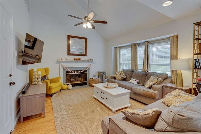 living room with ceiling fan, light hardwood / wood-style floors, and high vaulted ceiling