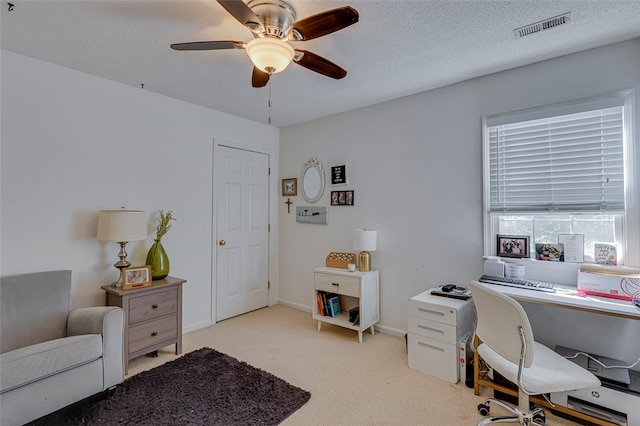 office space with light carpet, ceiling fan, and a textured ceiling