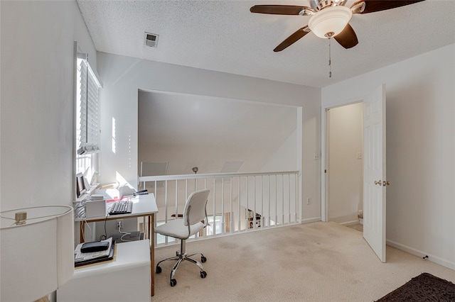 office space featuring a textured ceiling, a healthy amount of sunlight, ceiling fan, and light colored carpet