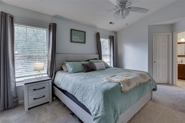 carpeted bedroom with connected bathroom, vaulted ceiling, and ceiling fan