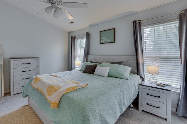 bedroom featuring lofted ceiling, multiple windows, light colored carpet, and ceiling fan