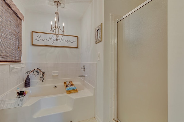 bathroom with an inviting chandelier and shower with separate bathtub