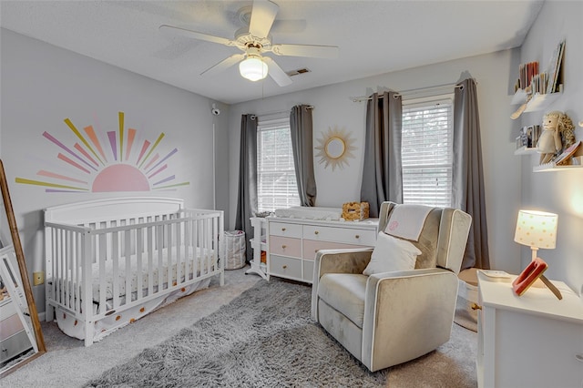 bedroom featuring ceiling fan, a nursery area, light carpet, and multiple windows