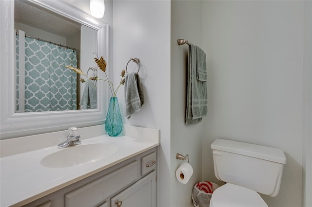 bathroom featuring a textured ceiling, vanity, and toilet