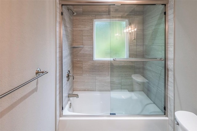 bathroom with bath / shower combo with glass door and toilet