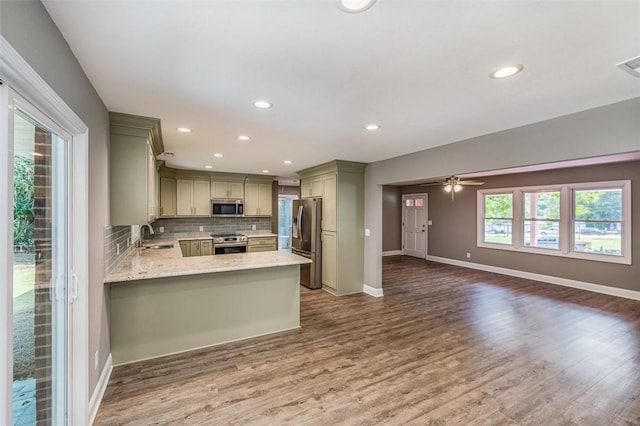 kitchen with hardwood / wood-style floors, sink, decorative backsplash, kitchen peninsula, and stainless steel appliances