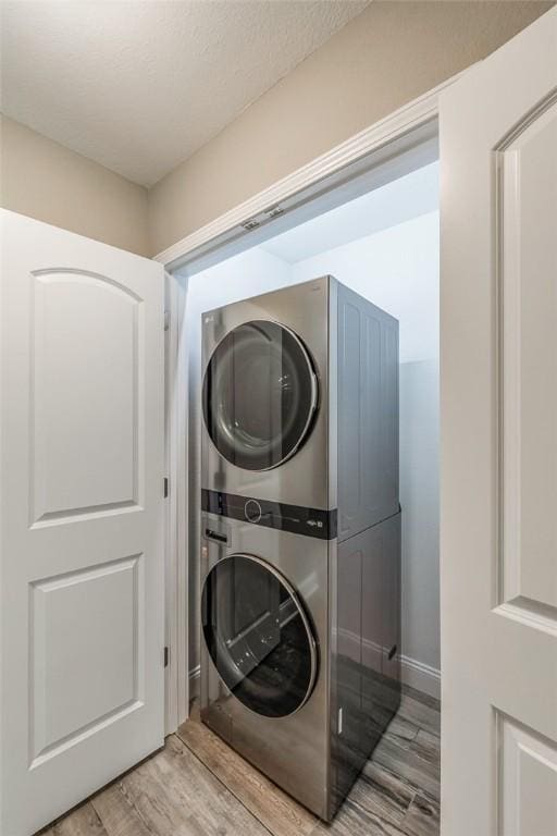 washroom with stacked washer and dryer, a textured ceiling, and light wood-type flooring