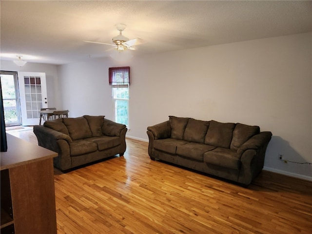 living room featuring light hardwood / wood-style floors, ceiling fan, and a textured ceiling