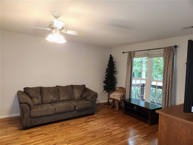 living room featuring ceiling fan, a textured ceiling, and light wood-type flooring