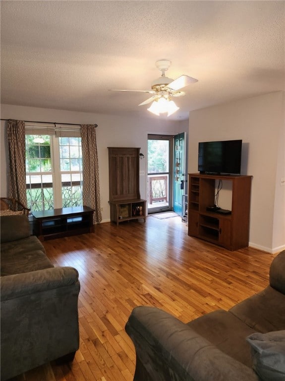 living room with a wealth of natural light, ceiling fan, hardwood / wood-style floors, and a textured ceiling