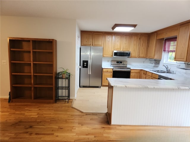 kitchen featuring sink, kitchen peninsula, light hardwood / wood-style flooring, decorative backsplash, and appliances with stainless steel finishes