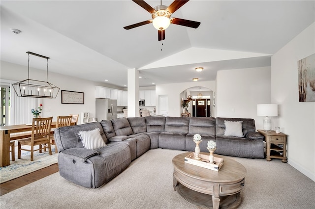 living room with light hardwood / wood-style floors, ceiling fan with notable chandelier, and lofted ceiling