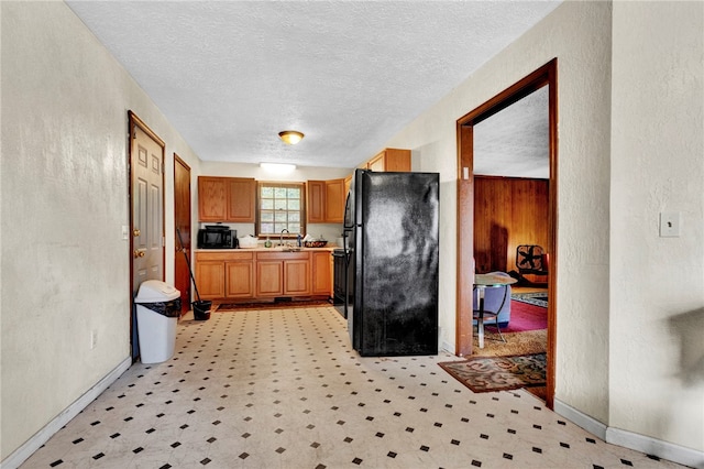 kitchen with black fridge, sink, and a textured ceiling