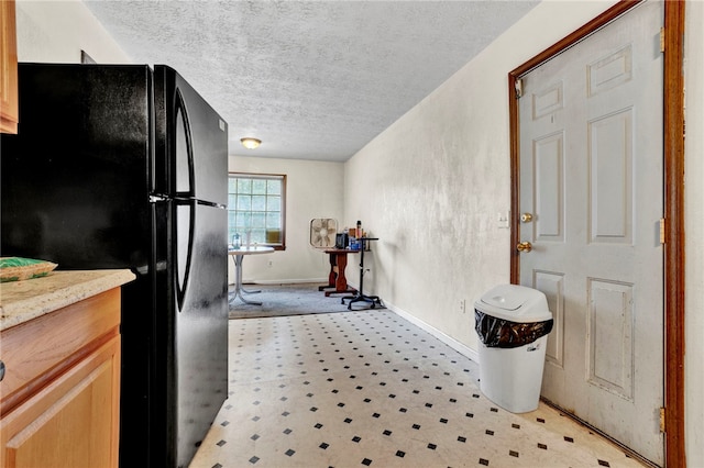 kitchen with black fridge and a textured ceiling