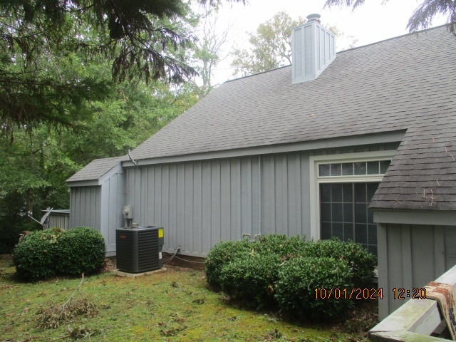 view of side of home with cooling unit and a lawn