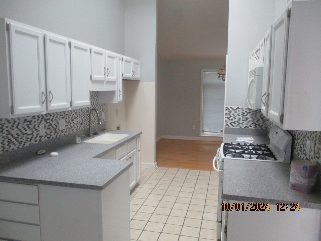 kitchen with decorative backsplash, white appliances, sink, and white cabinetry