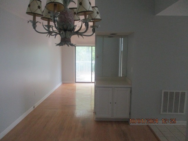 unfurnished dining area with an inviting chandelier and hardwood / wood-style floors